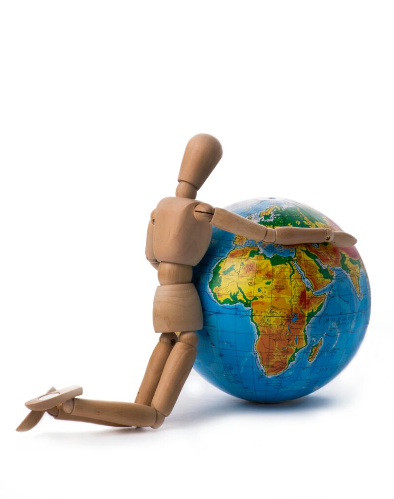 Wooden mannequin figure hugging a colorful globe, symbolizing global unity and peace.